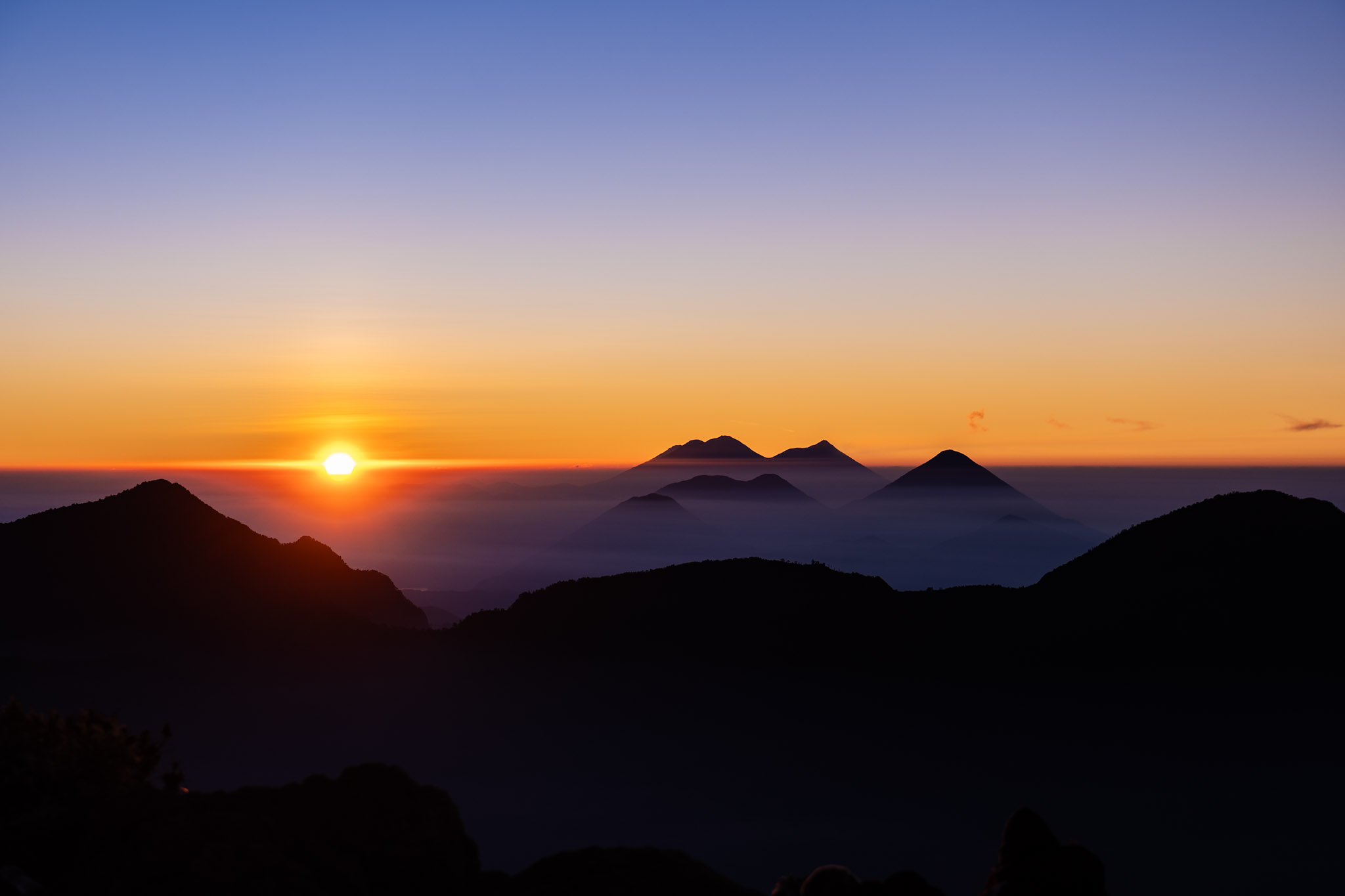 Sunrise lighting up the silhouettes of eight volcanoes along Guatemala’s volcanic chain, captured on a Santa María tour.